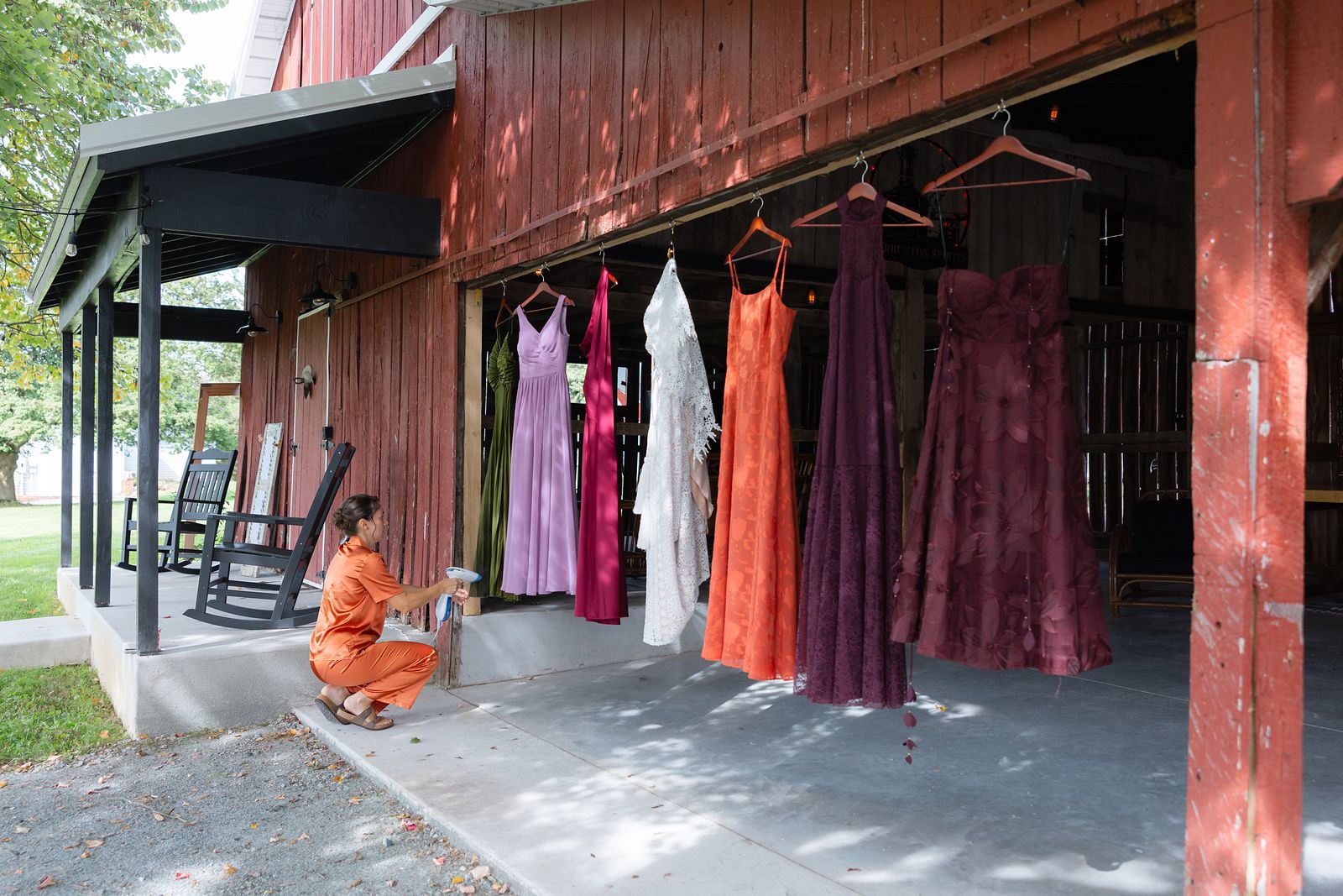 Bridesmaid dresses in burnt orange and eggplant hanging on the barn porch at Warburton Stables in Elkton, MD