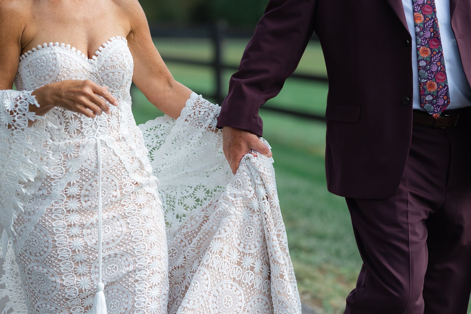 Detail of Shannon holding her lace dress beside Brian's burgundy suit