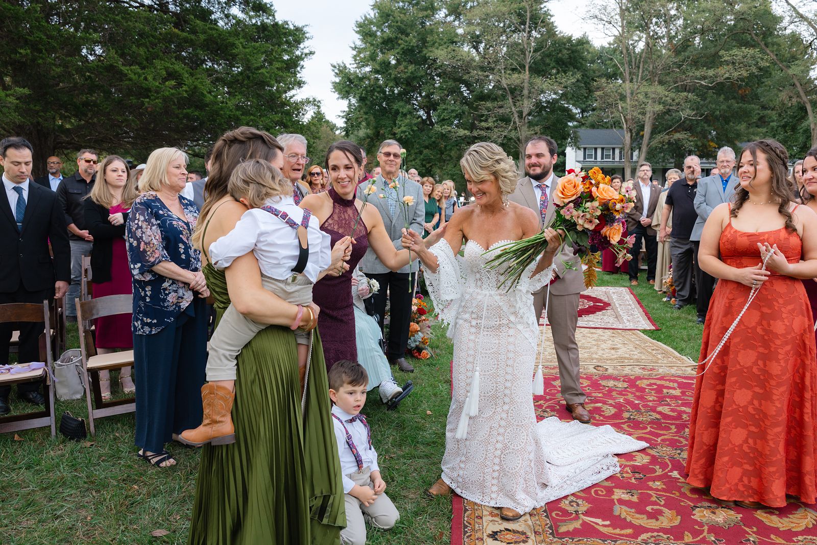 Shannon walking down the aisle with her children while guests hand her flowers