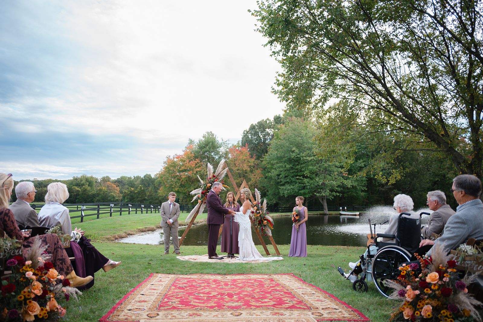 Wide view of the pond ceremony with the wedding party under the arch