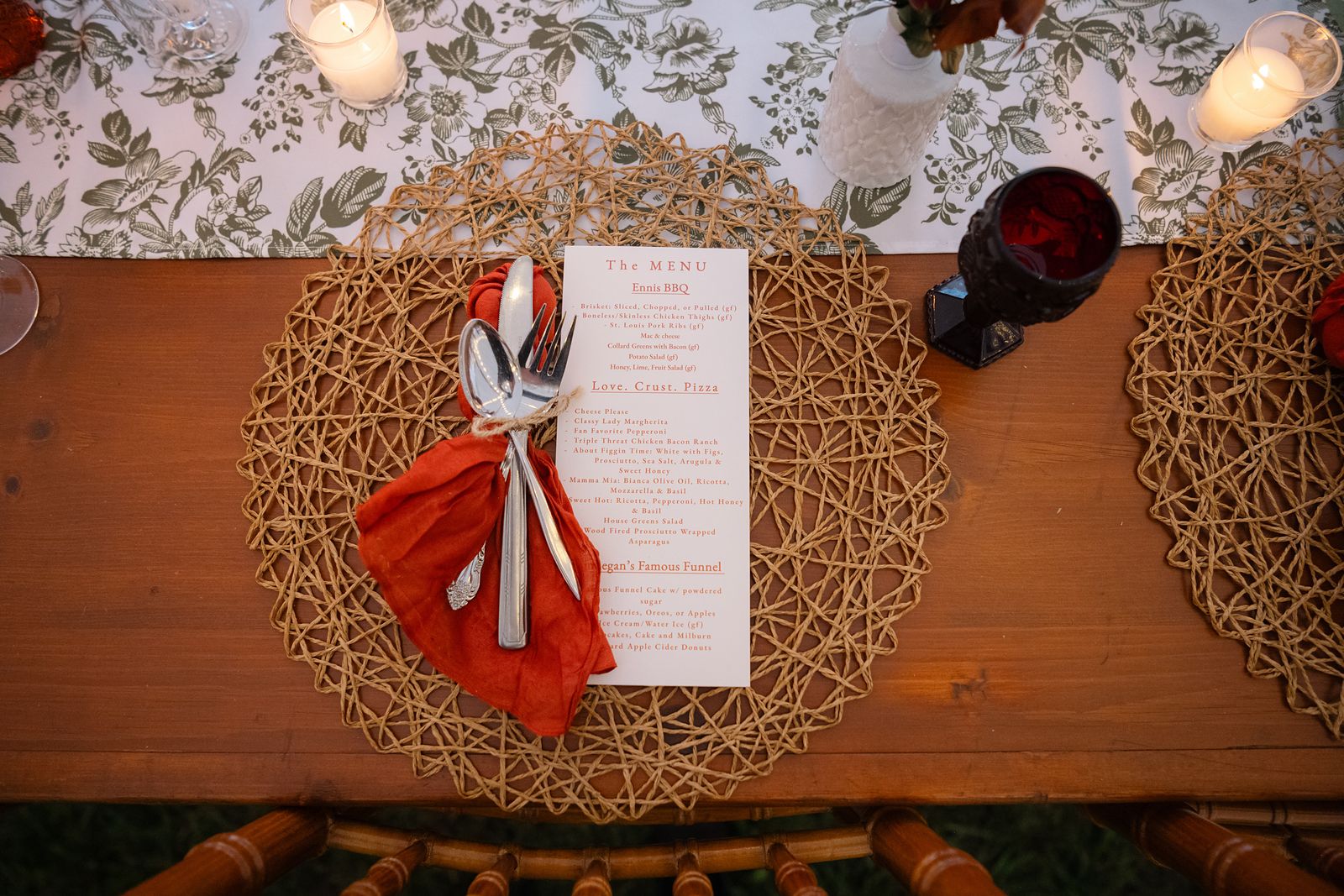 Place setting with a burnt orange napkin, wood charger, and printed menu